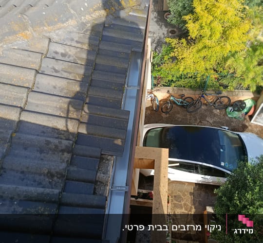 גג רעפים עם צל של עץ ורכב חונה למטה